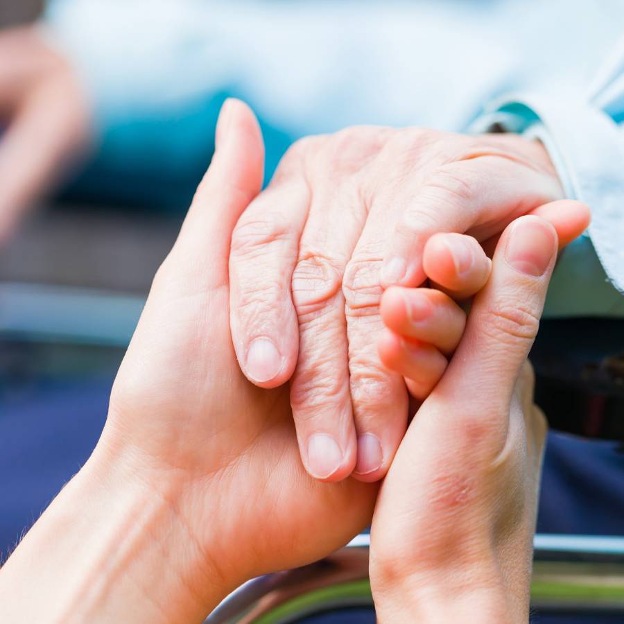 A young person's hand holding an elderly person's hand